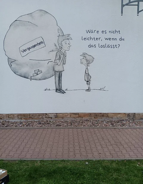 Schwarzweiße Wandzeichnung mit Figuren und Sprechblase