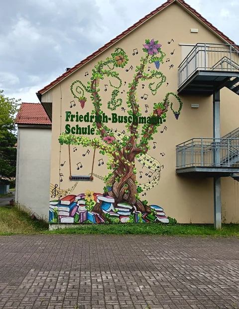Große Fassadengestaltung an einer Schule mit Pflanzen und Figuren